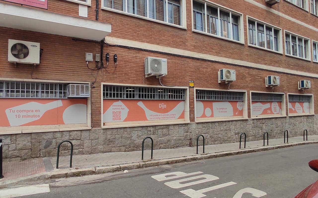 Imagen de varios escaparates decorados con vinilos de la tienda de reparto a domicilio DIJA